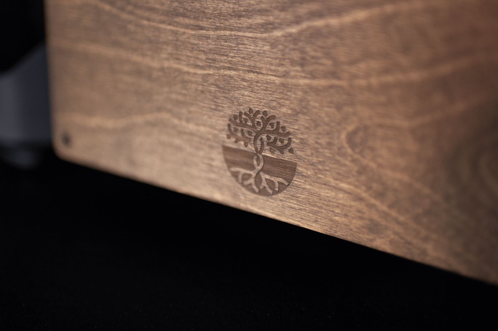 Close-up of engraved tree logo on the Tilia case's walnut wood panel
