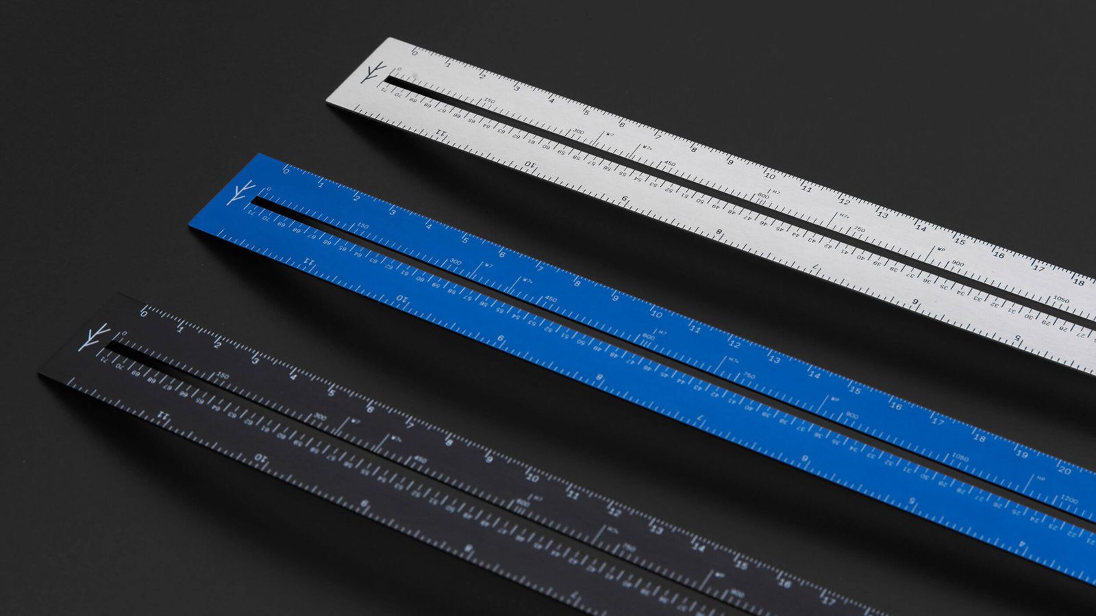 Three LindLund Alm rulers in silver, blue, and black on a dark background